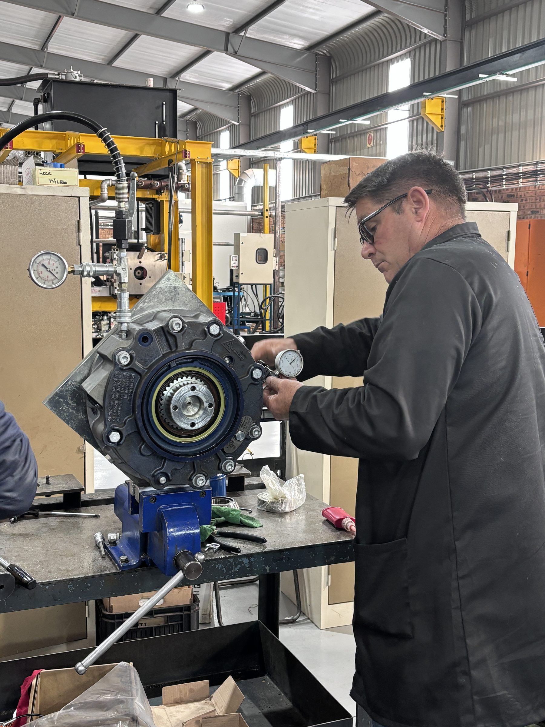 Axiom Hydraulics technician measuring a rebuilt Ausco brake assembly with a dial gauge